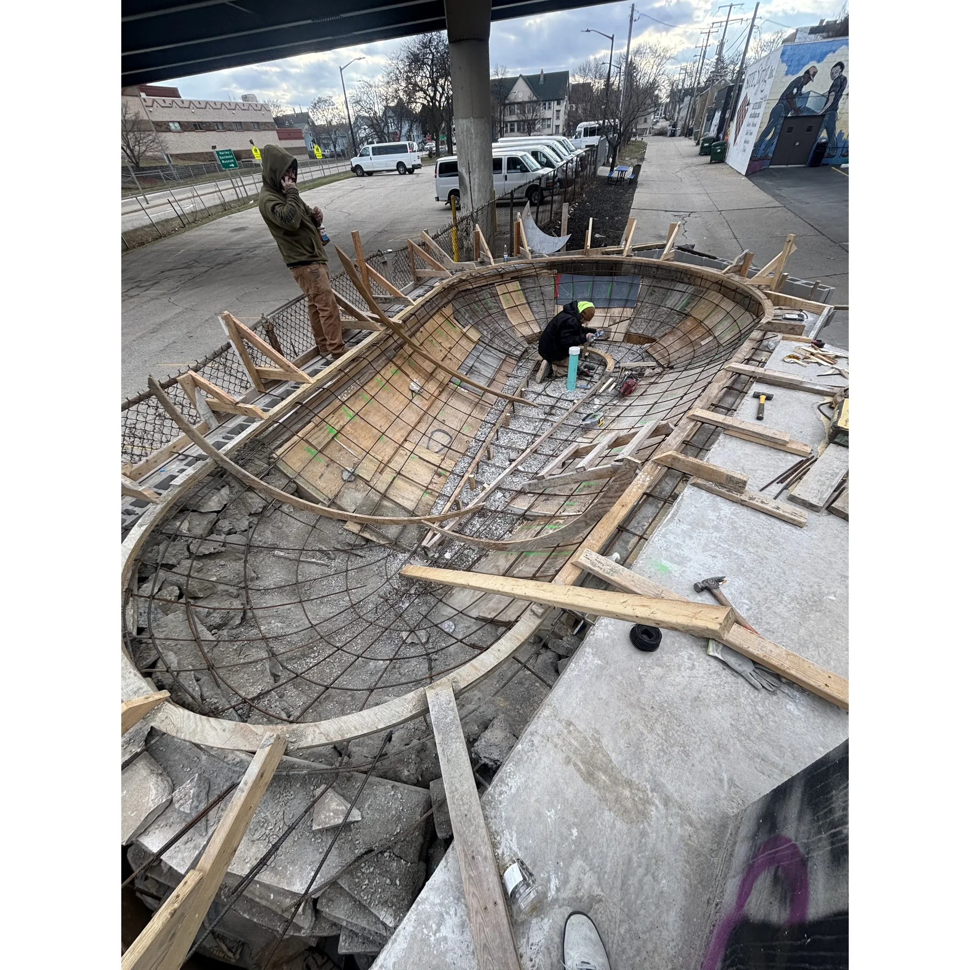 Volunteers pouring and finishing concrete on a new skateboarding obstacle at National DIY Skatepark in Milwaukee